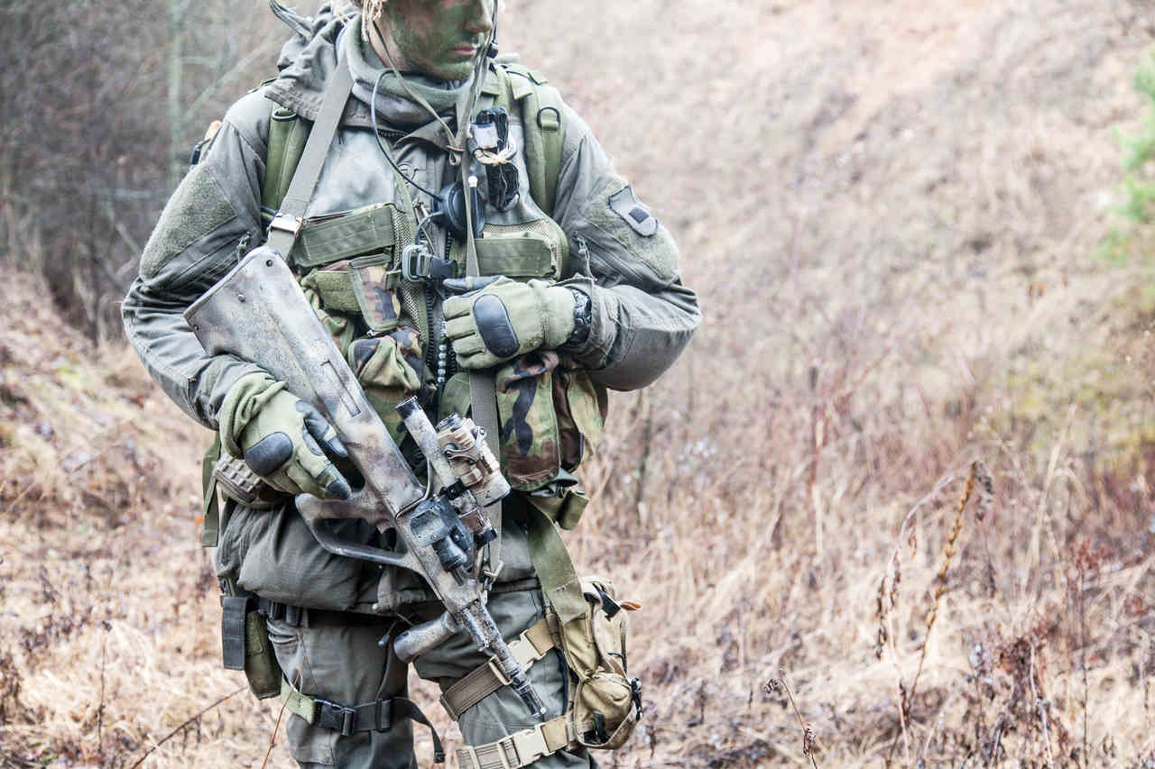 ormanlık alanda duran elinde silah olan bir komando asker