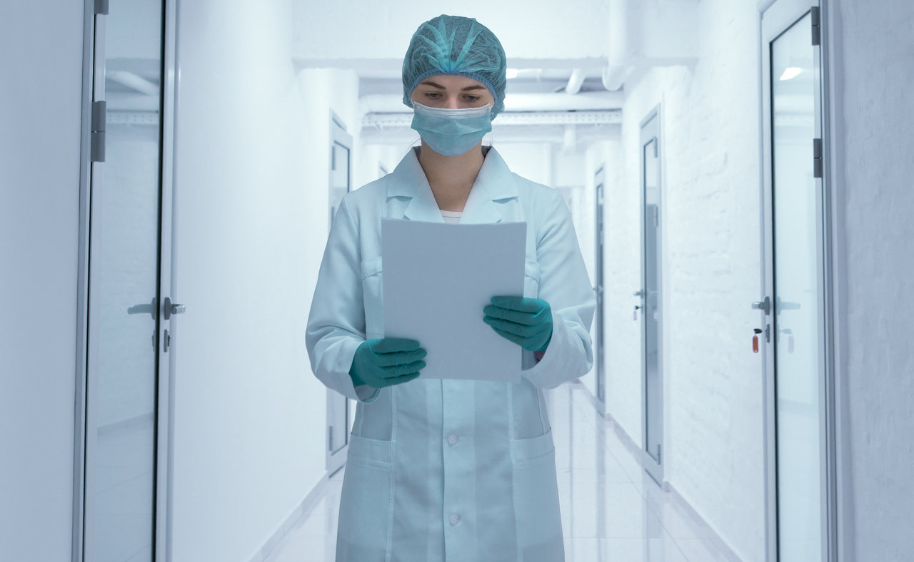 hastane koridorunda elindeki raporlara bakan kadın doktor